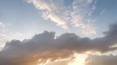 Güneş doğarken hareket eden kara bulutların zamanı, dramatik gökyüzünde yavaşça sıcak güneş ışığını açığa çıkarıyor, doğa ve hava görüntüleri için mükemmel..