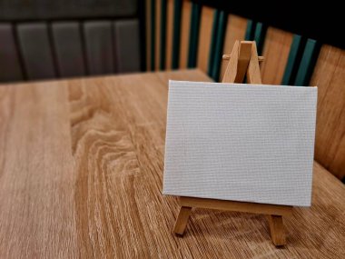 Rahat bir masada sehpası olan boş tuval, resim yapmaya hazır, sanat dersleri için mükemmel, hobi stüdyoları, ya da yaratıcı ev dekorasyonları.