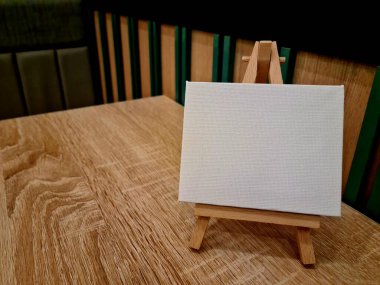 Rahat bir masada sehpası olan boş tuval, resim yapmaya hazır, sanat dersleri için mükemmel, hobi stüdyoları, ya da yaratıcı ev dekorasyonları.