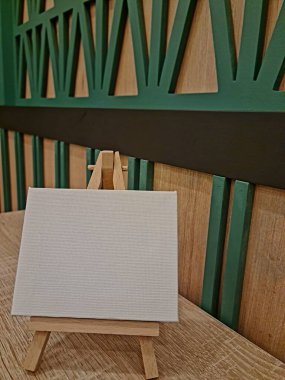 Rahat bir masada sehpası olan boş tuval, resim yapmaya hazır, sanat dersleri için mükemmel, hobi stüdyoları, ya da yaratıcı ev dekorasyonları.