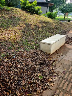 Düştükten sonra toplanan yapraklar. Kuru yapraklar bir araya toplanarak, sonbahar veya kurak mevsimde bahçede veya parkta mevsimsel temizlik yapıldığını gösteriyor..