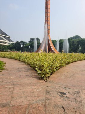 Yol bir parkta iki kıvrımlı yöne ayrılıyor. Yeşilliklerle çevrili çatallı yol, açık hava bahçe ortamında manzaralı bir seçim sunuyor..