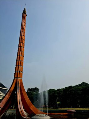 Bir parkta, etrafında fıskiyeler olan heykel dikiliyor. Mimari, su özellikleri ve yeşil manzarayı birleştiren popüler turistik cazibe.