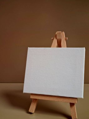 Bej arkaplana karşı duran boş beyaz tuval, sanat, model, yaratıcılık veya minimalist tasarım temaları için ideal.