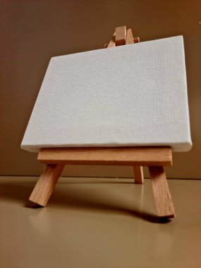 Bej arkaplana karşı duran boş beyaz tuval, sanat, model, yaratıcılık veya minimalist tasarım temaları için ideal.