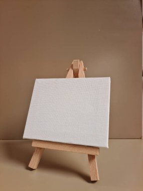 Bej arkaplana karşı duran boş beyaz tuval, sanat, model, yaratıcılık veya minimalist tasarım temaları için ideal.