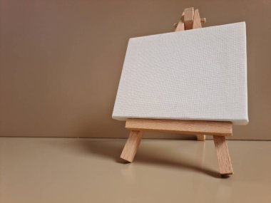 Bej arkaplana karşı duran boş beyaz tuval, sanat, model, yaratıcılık veya minimalist tasarım temaları için ideal.