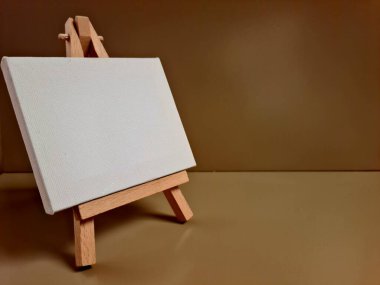 Bej arkaplana karşı duran boş beyaz tuval, sanat, model, yaratıcılık veya minimalist tasarım temaları için ideal.