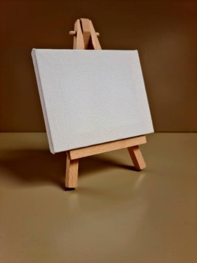 Bej arkaplana karşı duran boş beyaz tuval, sanat, model, yaratıcılık veya minimalist tasarım temaları için ideal.