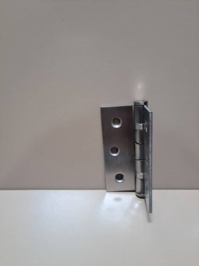 Bej arka planda paslanmaz kapı menteşesi. Kapı eklentisi için kullanılan metal menteşe bileşeni, inşaat veya donanım temaları için nötr yüzey ile izole edilmiş.