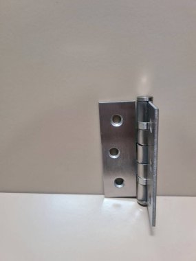 Bej arka planda paslanmaz kapı menteşesi. Kapı eklentisi için kullanılan metal menteşe bileşeni, inşaat veya donanım temaları için nötr yüzey ile izole edilmiş.