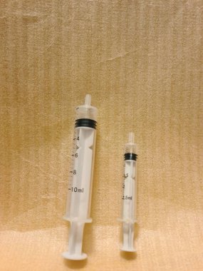 Yan yana farklı boyutlarda iki şırınga. Temiz yüzeye yerleştirilen tıbbi enjeksiyon araçları, klinik kullanım için hacim varyasyonunu gösterir.