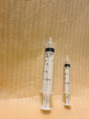 Yan yana farklı boyutlarda iki şırınga. Temiz yüzeye yerleştirilen tıbbi enjeksiyon araçları, klinik kullanım için hacim varyasyonunu gösterir.