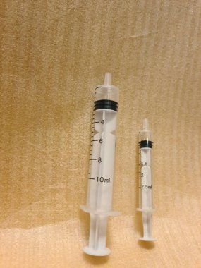 Yan yana farklı boyutlarda iki şırınga. Temiz yüzeye yerleştirilen tıbbi enjeksiyon araçları, klinik kullanım için hacim varyasyonunu gösterir.
