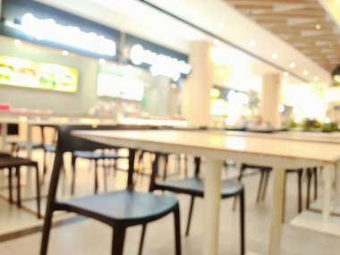 Modern bir alışveriş merkezinin içindeki bulanık ışıkları, masaları ve yumuşak kentsel atmosferdeki insanları gösteren yemek salonunun odak noktasından çıkarılmış hali..