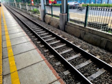 Tren istasyonu platformu yanında uzanan tren rayları, seyahat için ulaşım geçmişi, şehir ulaşımı ve kamu altyapısı.