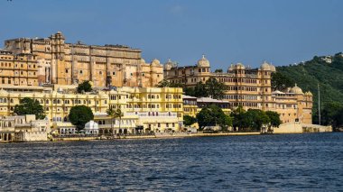 Pichola Gölü kıyısında şehir sarayı açık mavi gökyüzü altında, Udaipur, Rajasthan, Hindistan, Ağustos 2025.