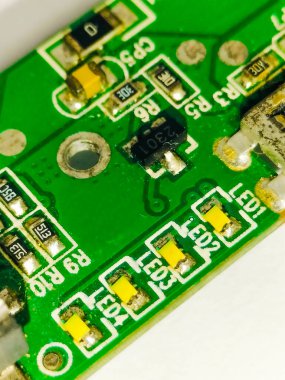Elektronik, teknoloji ve mikro devre mühendisliği uygulamalarında kullanılan sarı yüzeye monte edilmiş LED ve dirençli yeşil bir PCB 'nin makro görüntüsü..