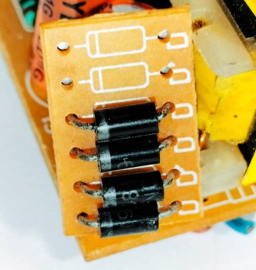 Makro resim dört siyah silindirik diyot lehimlenmiş bir PCB üzerinde gösteriyor. Elektronik devrelerde düzeltme, koruma ve voltaj kontrolü için kullanılır..