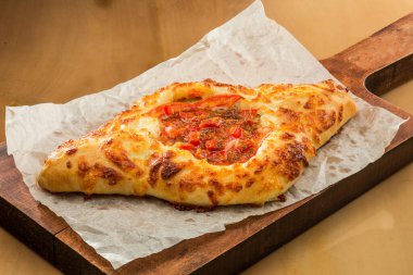 Geleneksel Gürcü pastası. Peynirli ve çiğ yumurtalı Adjarian Khachapuri. Khachapuri 'nin ahşap arka planda kırsal bir tarzı var. Malzemeli Adjara Khachapuri. Gürcistan mutfağı