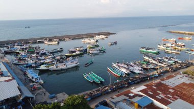 The calm waters of the bay cradle a collection of weathered wooden fishing boats, their timeworn hulls bearing the marks of countless journeys across the sea