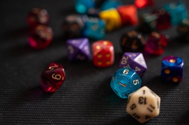 Masaüstü RPG 'leri için renkli çokyüzlü zar koleksiyonunun yakın çekimi. Keskin odak noktası canlı, şeffaf bir mavi zar, oyun hobisinin eğlence ve heyecanını temsil ediyor.