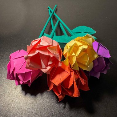 Pembe, sarı, mor, açık pembe ve turuncu, yeşil saplı ve yapraklı beş origami gülü..