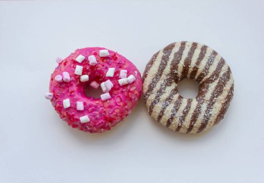 Beyaz arka planda iki çörek, tatlı donutlar, çikolatalı çörek ve şekerli pembe çörek.