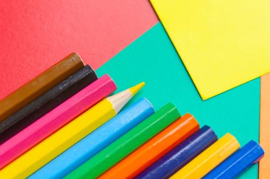 Çok renkli kağıt üzerine çok renkli kalem ve kalemler yakın plan, fotoğraf arkaplanı, okula dönüş, metin için boş alan