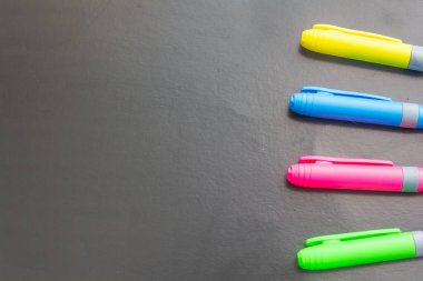 Siyah kağıt üzerine çok renkli kalem ve kalemler yakın plan, fotoğraf arkaplanı, okula dönüş, metin için boş alan