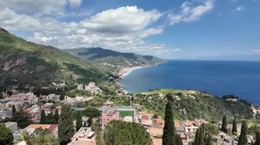 Sicilya, İtalya 'daki Taormina kıyılarını gösteren pürüzsüz bir soldan sağa tava, açık mavi gökyüzünün altındaki ikonik Isola Bella' da sona eriyor.