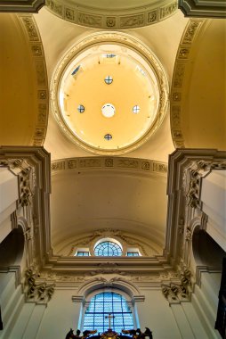 Kubbe tavanının çarpıcı görüntüsü, karmaşık mimari detaylar, zarif pervazlar ve dairesel tavan penceresi. Işık filtreler, boşluğu aydınlatır..