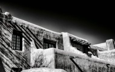 Güneybatı kerpiç binasının desenli duvarları ve ahşap kirişleri olan tek renkli bir fotoğrafı..