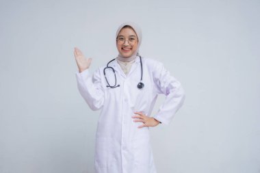 Beyaz önlüklü ve steteskoplu güzel bayan doktor kameraya gülümsüyor. beyaz arkaplanda izole.