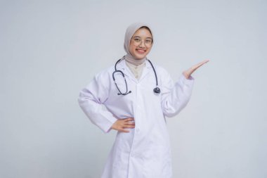 Kadın doktor beyaz bir elbise giyip bir şeyi işaret ediyor..