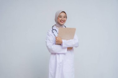 Başörtülü Müslüman kadın doktor elinde bir pano tutuyor.