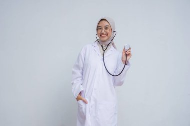 ... tesettür ve steteskop takan genç, güzel Müslüman kadın doktor fotokopi alanını gösterirken gülümsüyor.