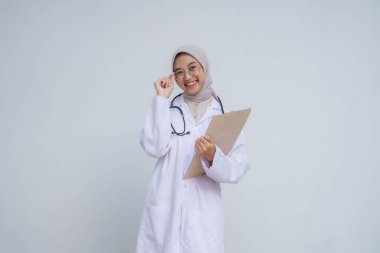 Üniformalı genç Asyalı Müslüman doktor beyaz arka planda steteskop tutuyor.