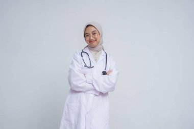 Beyaz önlüklü bir kadın doktor portresi beyaz arka planda kollarını kavuşturmuş duruyor.