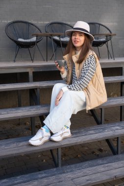 Şapkalı güzel esmer ve sonbahar giysisi ve açık havada bir fincan kahve..