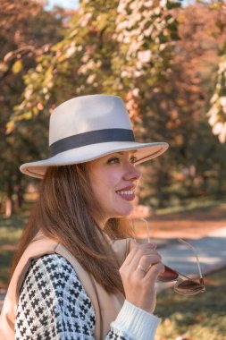 Sonbahar parkında şapkalı ve sonbahar elbiseli güzel bir esmer..