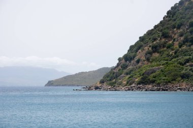 Gün ışığında kıyı yamacının yakınındaki sakin deniz suları.