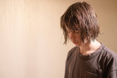 13 yaşında, ıslak, dağınık saçlı bir çocuk aşağıya bakıyor, düşüncelere dalmış. Oda, düşünceli atmosferi geliştiren sıcak ışığın tadını çıkarıyor..