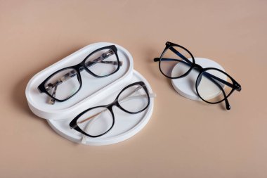 Kahverengi arka planda gözlüklü alçıtaşı elementleri. Optik mağaza, görüş testi, şık gözlük konsepti üst görünüm, düz yatak.