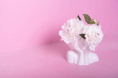 Beyaz şakayık çiçekli kafa şeklinde yaratıcı alçı vazo. Akıl sağlığı konsepti.