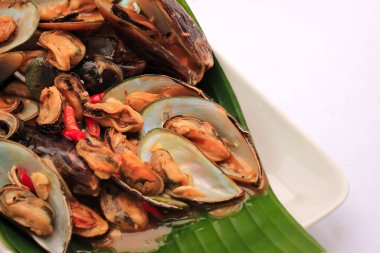 Muz yaprağına sarılı istiridye deniz ürünleri. İstiridye deniz ürünleri beyaza izole edilmiş. İstiridye yemeği balık ve midyedir. İstiridye deniz ürünleri popüler yemektir ve çok lezzetlidir.