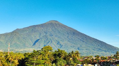 Ciremai Dağı 'nın parlak mavi arkaplanlı gölgeli ağaçlarla süslenmiş görüntüsü
