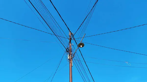 Karışık kablolu elektrik direği ve temiz ve parlak mavi gökyüzü arka planlı sokak lambaları.