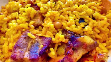 Lezzetli bir kasede taze tavuk ve nohut ile kaplanmış renkli sarı pirinç tabağı.