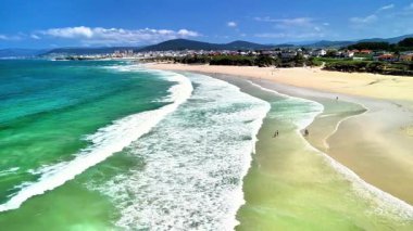 Kumlu sahil şeridi boyunca nefes kesici, berrak turkuaz suların sergilendiği nefes kesici bir hava manzarası.